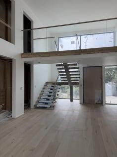 Floating stair rises to a loft lined with frameless glass in a double-height room