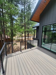 Composite deck edged with black cable railing looking out to ponderosa pines