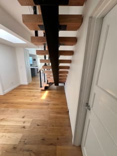 Black mono stringer with thick red oak treads seen from below in a long hallway