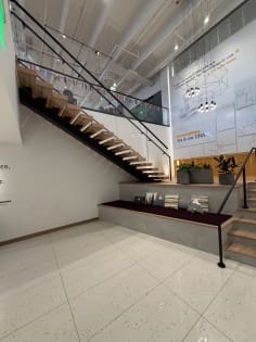 Wood floating stair on a black stringer with frameless glass and black handrail in a modern office atrium