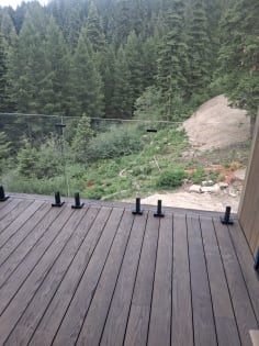 Deck glass railing with spigots over forest