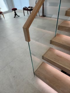 Close view of oak floating treads with LED lighting, Vedera glass and a wood top cap