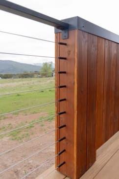 Express cable runs terminate with DriveTite fittings into a cedar-clad post overlooking a mountain pasture.