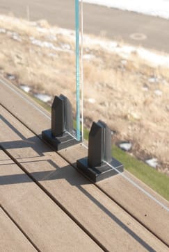 Close view of black talon spigots clamping frameless glass on a composite deck.