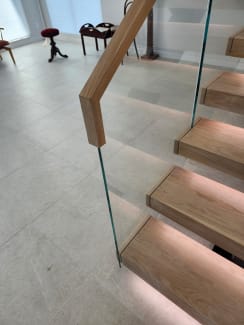 Close view of oak floating treads with LED lighting, Vedera glass and a wood top cap