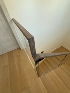 Frameless glass on standoff pins with a dark wood handrail turning down a white oak stair
