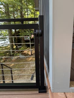 Black aluminum gate with horizontal rod infill at the top of exterior stairs
