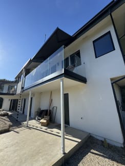 Frameless base rail glass balcony on a white stucco hillside home