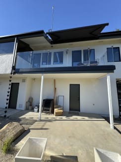 Long frameless glass balcony with dark fascia on a white stucco home