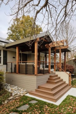 Cedar-post covered porch with cable railing and wide composite steps on a craftsman home.
