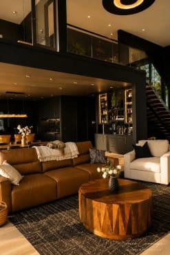 A black FLIGHT Mono with glass railing rises behind a leather sofa in a moody dark-walled great room.