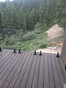Deck glass railing with spigots over forest