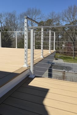 White-post cable railing frames a two-level composite deck against a clear blue sky