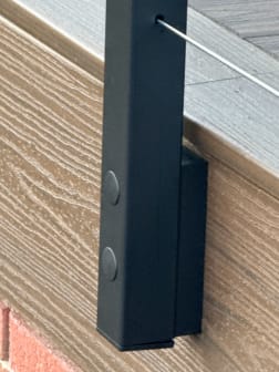 Close-up of a black side-mounted cable post fastened to a composite deck fascia.