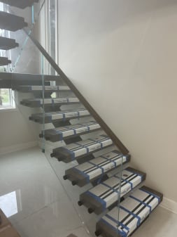 Floating stair in clean Viewrail tread covers with frameless standoff-pin glass and wood handrail