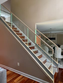 Frameless base rail glass with an oak cap runs up a  stair beside a dining room
