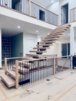 White oak FLIGHT Mono stair with floating treads rising past a balustraded loft