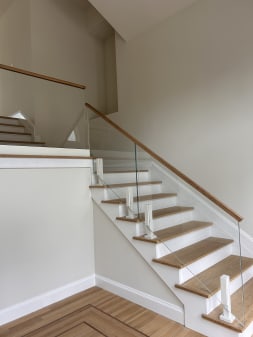 Frameless glass on white posts with an oak top cap along a white oak stair