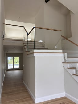 Glass railing with oak cap on white posts along a split-level stair toward a pool door