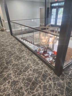 Frameless glass railing wraps a mezzanine opening above a lobby in a commercial building