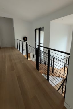 Black rod railing wraps a stair opening on a white oak upper floor