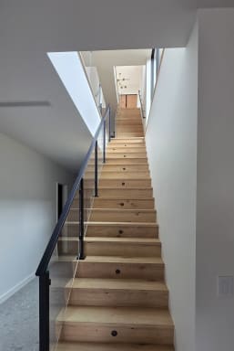 Long straight oak stair with black cable railing under a skylight