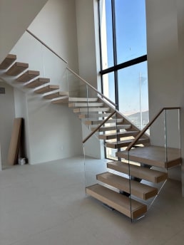 Floating stair with glass railing in a tall window bay