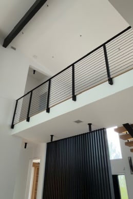 Black rod railing on an interior loft balcony beneath a vaulted ceiling