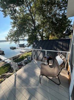 White cable railing wraps a composite balcony with a lounge chair looking over docks on a calm lake.