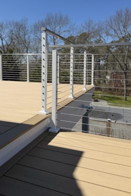 White-post cable railing frames a two-level composite deck against a clear blue sky