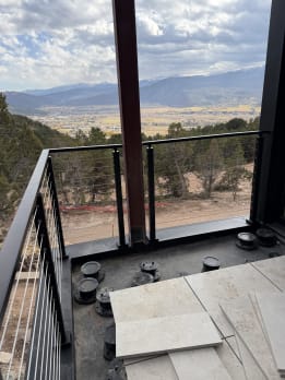 Black cable railing corner on a balcony looking out over a mountain valley