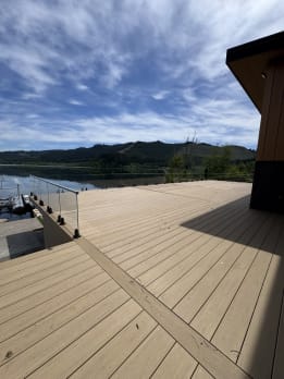 Large composite deck edged with talon-mounted glass looking out to forested hills and a lake