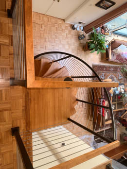 Overhead view of a wood spiral stair with black curved cable railing above parquet floors.