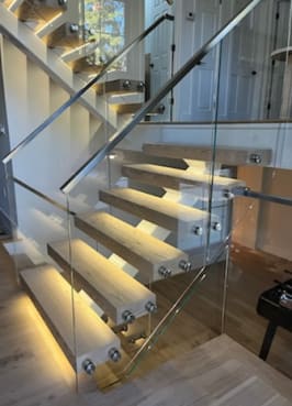 White mono stringer with light oak LED-lit floating treads and frameless glass on stainless standoff pins.