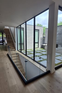 Base rail glass around a stair opening beside a glass wall looking onto a courtyard