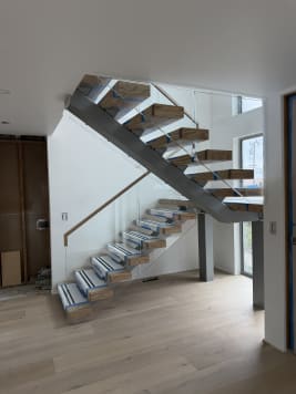 Steel center-stringer switchback stair with thick wood treads and glass railing in a bright entry