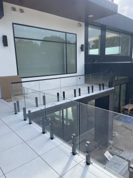 Rows of frameless glass on black talon spigots edge a white-tiled terrace