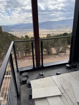 Black cable railing corner on a balcony looking out over a mountain valley