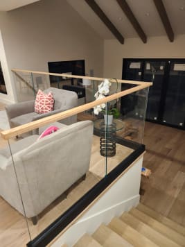 Black base rail glass with a wood top cap wraps a stair opening beside a living room seating area