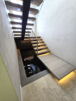 Mono stringer floating stair with a wide LED-lit landing over a reflecting pool