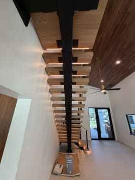 Long black mono stringer with LED-lit oak treads under a walnut ceiling