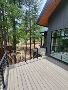 Composite deck edged with black cable railing looking out to ponderosa pines