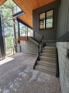 Black cable railing follows composite exterior stairs up to a cantilevered deck