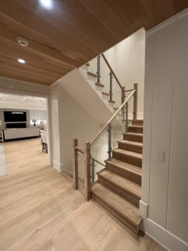 White oak stair with post-mounted glass and wood newels beside a paneled wall