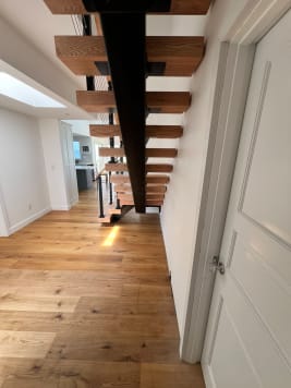 Black mono stringer with thick red oak treads seen from below in a long hallway