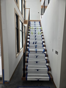 Straight floating stair in clean Viewrail tread covers with black rod railing beside tall windows
