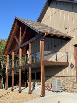 Timber-frame gable porch with a black-post glass balcony railing
