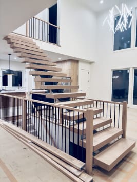 White oak floating stair on a mono stringer with traditional oak newels and black balusters in a bright great room