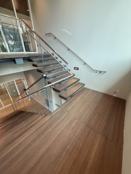 A dark wood landing with glass railing and stainless handrails in a commercial stairwell.