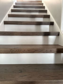 Dark oak thick-nose replacement treads over white risers climb a narrow stair.